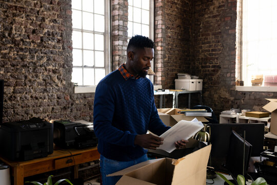 African American man organizing documents in office, focusing on paperwork tasks