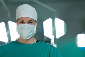 Medical professional in surgical attire focusing under bright operating room lights, copy space