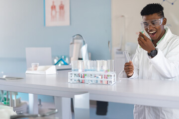 Teenager in school lab conducting experiment with test tubes, wearing safety goggles