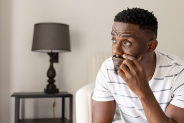 Contemplating ideas, thoughtful man sitting at home, looking up in contemplation, copy space