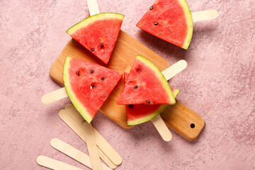 Wooden board with sweet watermelon sticks on pink background