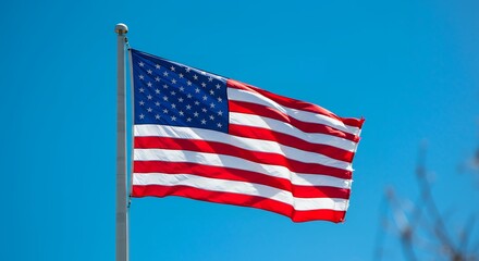 Obraz premium American Flag Waving Against Clear Blue Sky Symbol of Freedom
