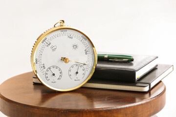 Aneroid barometer and books on table in room, closeup