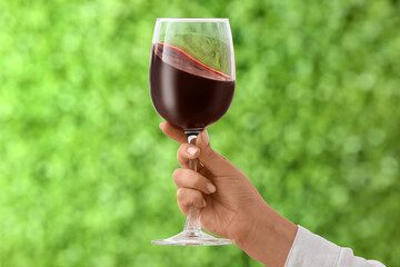 Female hand with glass of exquisite red wine outdoors, closeup