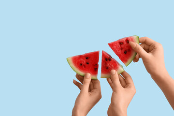 Female hands with slices of ripe watermelon on blue background