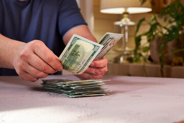 a man counting dollars on a light table, side view