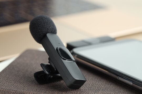 Lavalier microphone, smartphone with wireless receiver and notebook on table, closeup