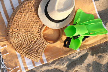 Towel with hat, bag and flippers on sand, closeup © Pixel-Shot