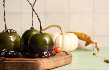 Wooden board of tasty caramel apples for Halloween on table