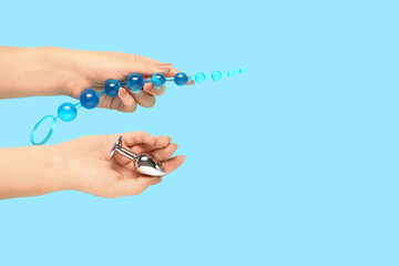 Female hands with anal plugs on turquoise background