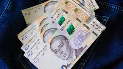 Ukrainian banknotes arranged artistically within a denim pocket, showcasing currency detail and fabric texture