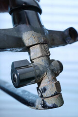 A rusty water faucet. Outdated plumbing. A broken faucet with lime coating.