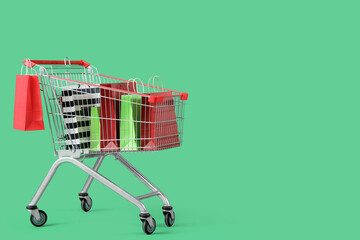 Shopping bags in cart on green background