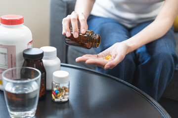 Dietary supplement concept, happy asian young woman hand holding fish oil pills, drugs medical tablet pouring capsules from medication bottle, take vitamin treatment for skin, hair at home, healthcare