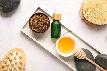 Composition with tray, spa stones, honey, bottles of essential oil and body massage tools on white background