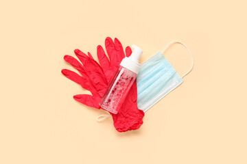Rubber gloves with bottle of sanitizer and mask on pale yellow background