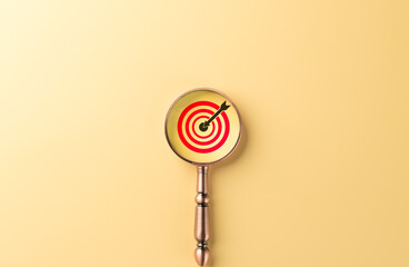 Focused business goal and target concept. A magnifying glass zoomed in on red bullseye with an...