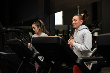 Determined women running on treadmills doing cardio workout at gym