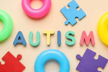 Word AUTISM and educational toys on beige background. Top view