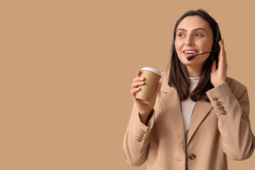 Female technical support agent in headset with paper cup of coffee on brown background