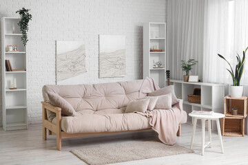 Beautiful interior of white living room with soft sofa, coffee table, shelving units and pictures