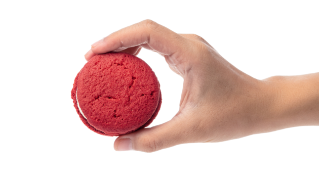 A close-up shot of a hand holding a delicious red velvet sandwich cookie