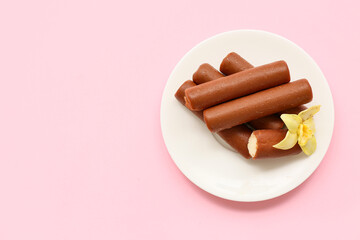 Plate with tasty chocolate glazed curd snacks with vanilla flavor on pink background