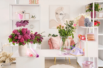 Shelving units with table and vases of beautiful flowers in florist studio