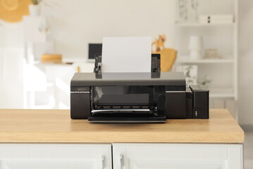 Modern printer on table in light office