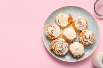 Plate with tasty cinnamon rolls on pink background