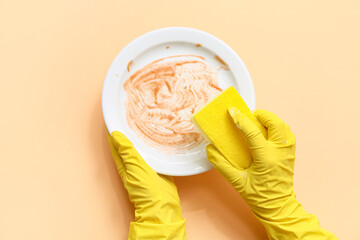 Hands washing dishes on beige background