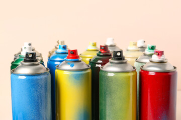Many spray paint cans on beige background