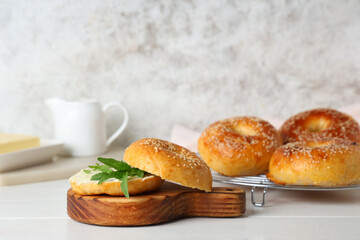 Board of tasty bagels with butter and arugula on white wooden table