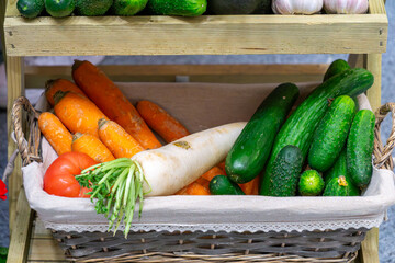 natural vegetable decoration on a wooden shelf in a basket. nicely arranged cucumbers, carrots and tomatoes. presentation of vegetables at fairs. product photography. healthy food