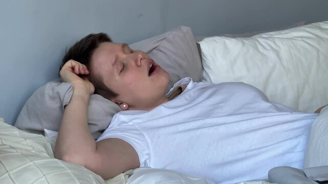 young woman sleeps in bed during the day and has breathing problems, apnea, open mouth, snoringyoung woman sleeps in bed during the day and has breathing problems, apnea, open mouth, snoring