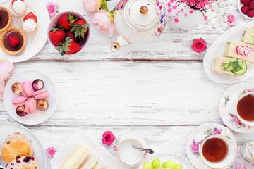 Afternoon tea frame against a white wood background. Vintage tea set, finger sandwiches, scones,...
