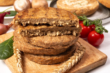Round vegetarian patties or burgers made from grains, vital wheat gluten food, uncooked and grilled