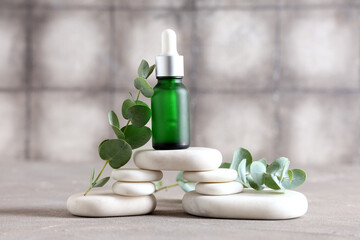 Spa stones and bottle of eucalyptus essential oil on grunge background, closeup