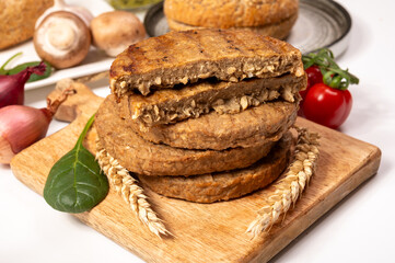 Round vegetarian patties or burgers made from grains, vital wheat gluten food, uncooked and grilled