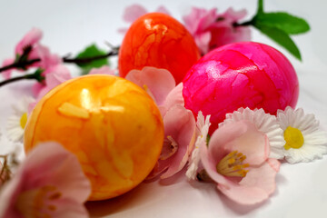 Brightly colored Easter eggs among spring flowers made of fabric