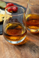 Whiskey and cheese pairing, tasting whisky glasses and plate with sliced crumbly old blue stilton and blue shropshire cheeses, Great Britain food and drink