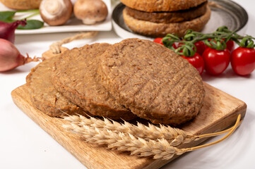 Round vegetarian patties or burgers made from grains, vital wheat gluten food, uncooked and grilled
