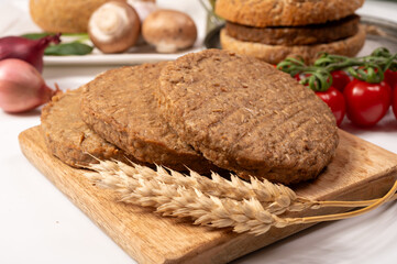 Round vegetarian patties or burgers made from grains, vital wheat gluten food, uncooked and grilled