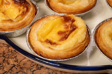 Portugal's traditional sweet dessert Pastel de nata egg custard tart pastry in cup close up on wooden background