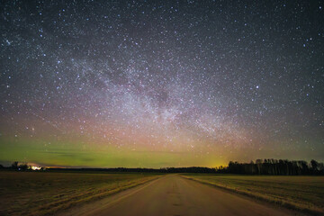 Country road at night with a gorgeous starry sky where the Milky Way is visible on a small northern light