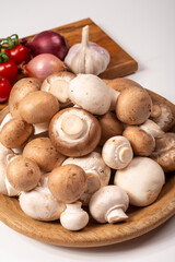 White and brown champignons mushrooms fresh uncooked on wooden plate copy space on white background