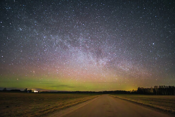 Country road at night with a gorgeous starry sky where the Milky Way is visible on a small northern light