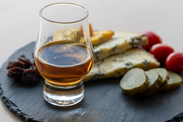 Whiskey and cheese pairing, tasting whisky glass and plate with sliced blue stilton and blue shropshire cheeses, Great Britain food and drink