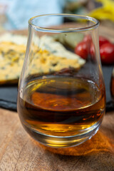 Whiskey and cheese pairing, tasting whisky glasses and plate with sliced crumbly old blue stilton and blue shropshire cheeses, Great Britain food and drink