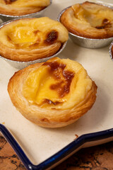 Portugal's traditional sweet dessert Pastel de nata egg custard tart pastry in cup close up on wooden background